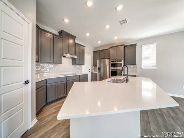 a large kitchen with stainless steel appliances a large counter top a stove a sink a refrigerator and a refrigerator