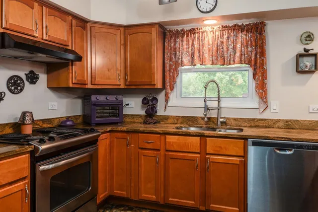 a kitchen with stainless steel appliances granite countertop a stove a sink and a microwave