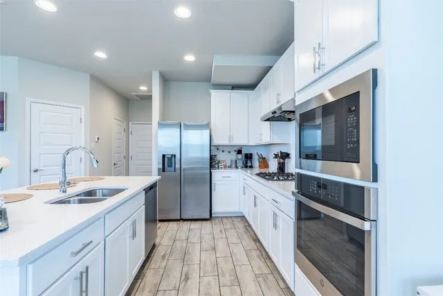 a kitchen with stainless steel appliances a sink cabinets and wooden floor