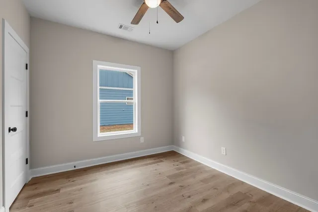an empty room with a window and a ceiling fan