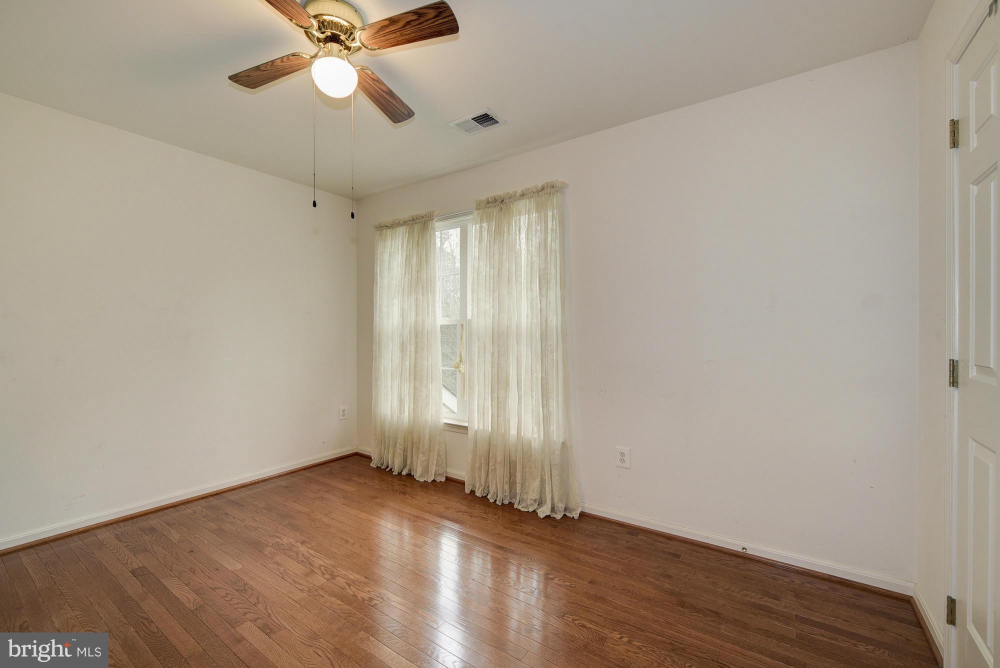 11204 Snowden Pond Road Laurel, MD 20708 - Photo 18 of 30 an empty room with wooden floor fan and windows