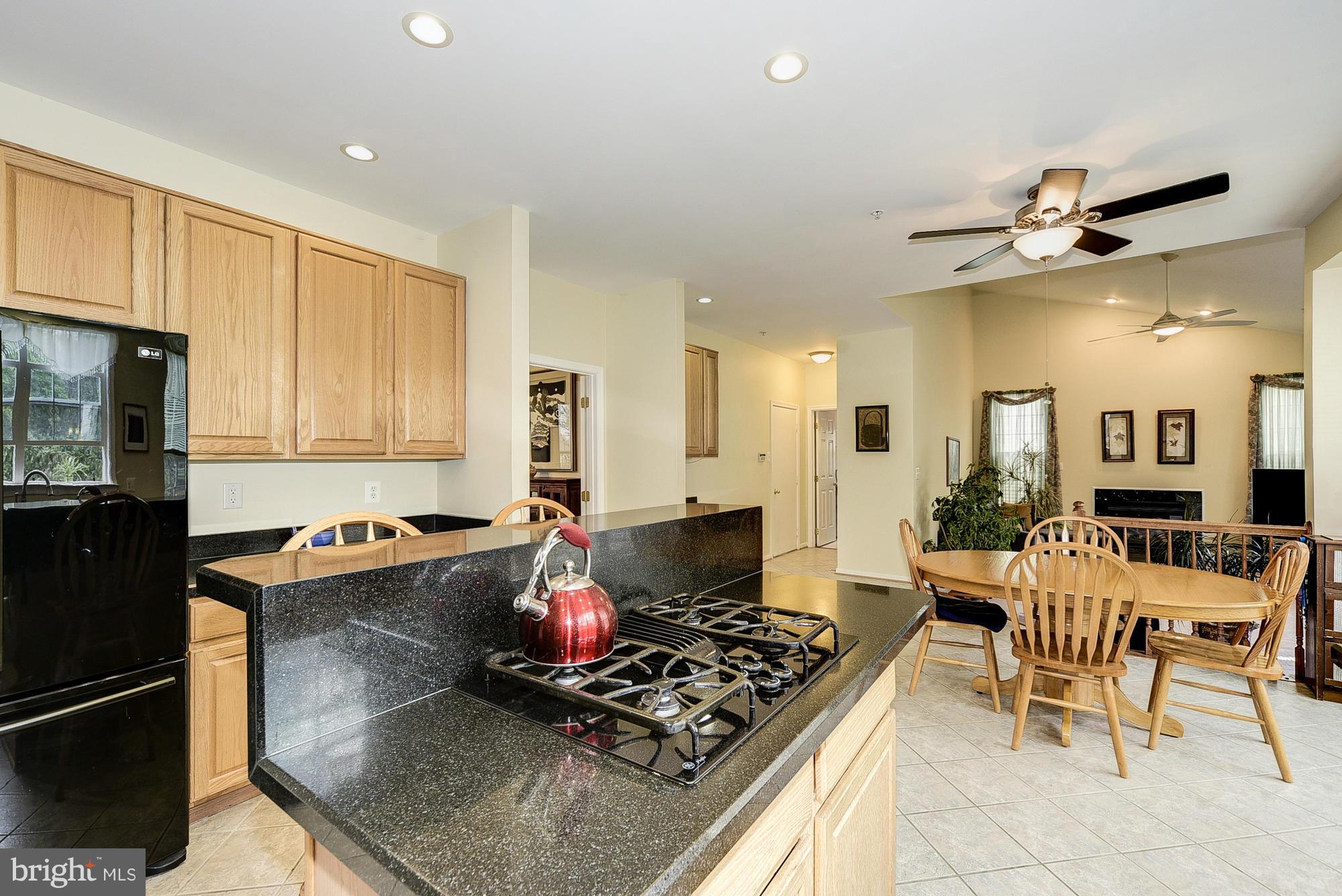 11204 Snowden Pond Road Laurel, MD 20708 - Photo 10 of 30 a kitchen with stainless steel appliances granite countertop a stove top oven a sink a dining table and chairs with wooden floor