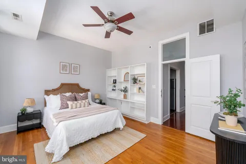a bedroom with a bed wooden floor and a potted plant