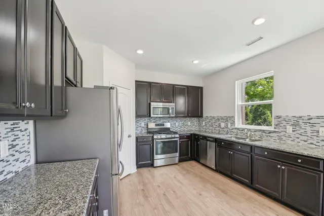 a kitchen with stainless steel appliances granite countertop a sink stove and refrigerator