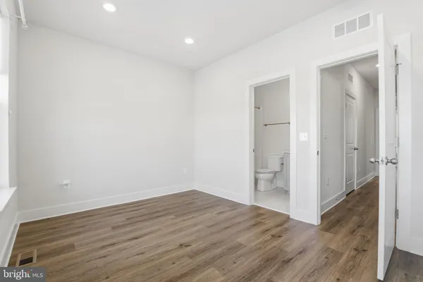 a view of an empty room with wooden floor and closet