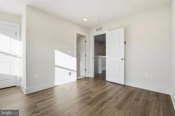 an empty room with wooden floor & windows