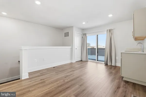 a view of an empty room with wooden floor and a cabinet