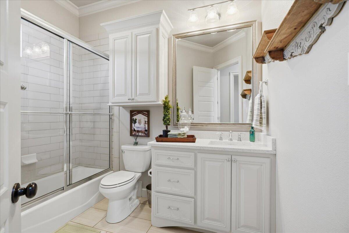 1202 North 14th Place Wolfforth, TX 79382 - Photo 43 of 75 a bathroom with a toilet a sink a glass door a shower and a mirror