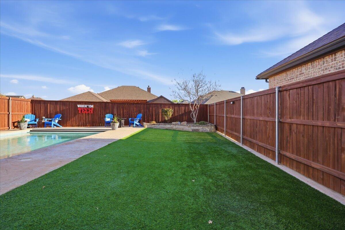 1202 North 14th Place Wolfforth, TX 79382 - Photo 67 of 75 a view of a yard with a table and chairs under an umbrella