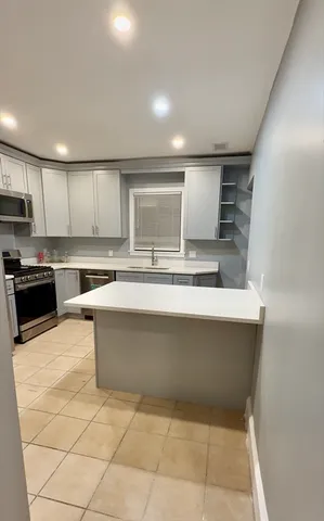 a large kitchen with kitchen island a sink a counter top stainless steel appliances and cabinets