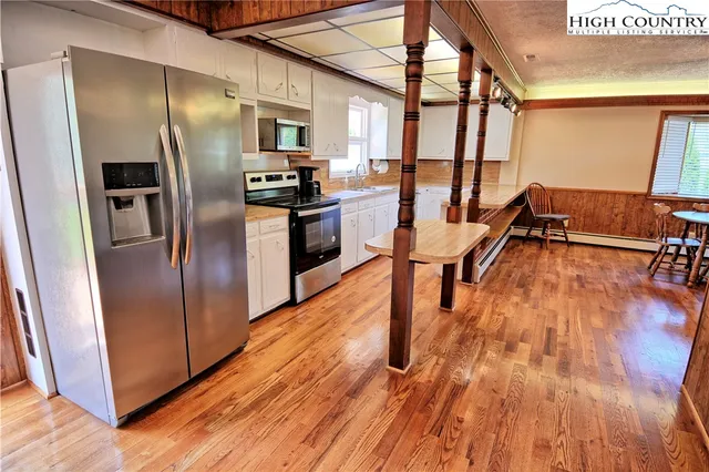 a kitchen with stainless steel appliances wooden floor and a refrigerator