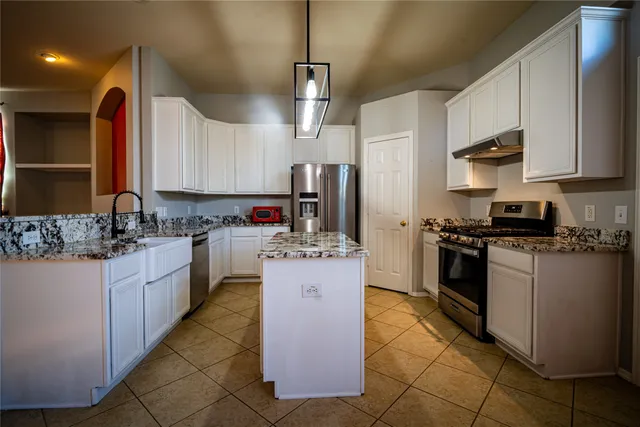 a kitchen with kitchen island granite countertop a sink cabinets and stainless steel appliances