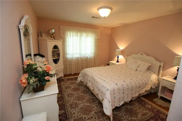 a bedroom with bed mirror and window