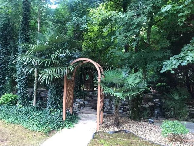 a backyard of a house with table and chairs plants and large trees