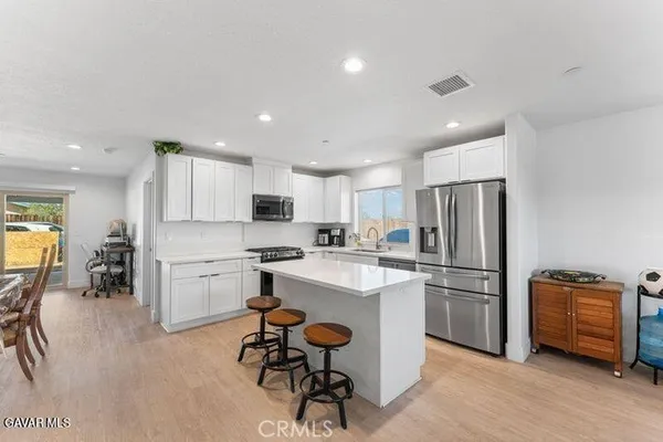 a kitchen with a refrigerator a stove and a dining table with wooden floor