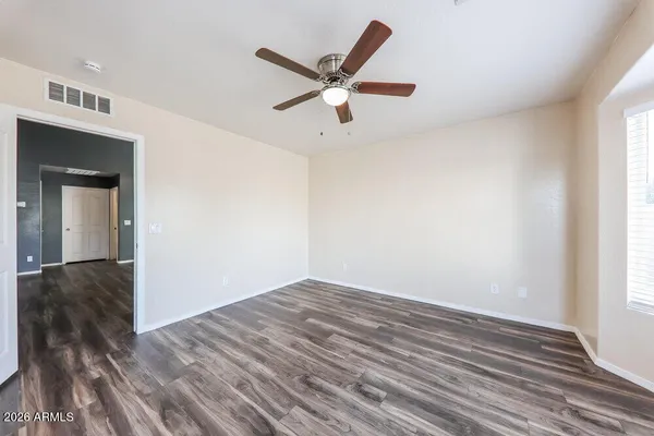 a view of empty room with wooden floor and ceiling fan