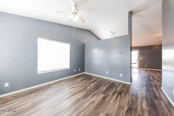 a view of empty room with wooden floor and fan