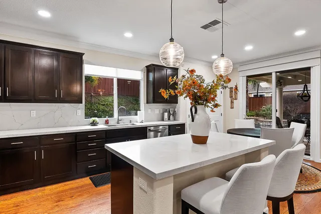 a kitchen with stainless steel appliances kitchen island granite countertop a table chairs and a refrigerator