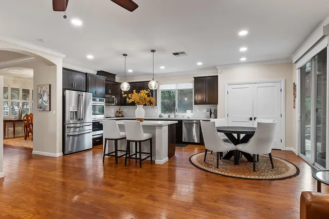 a kitchen with stainless steel appliances kitchen island granite countertop a refrigerator a stove a kitchen island with a dining table and chairs