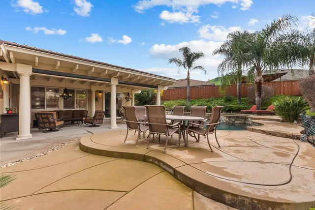 a view of a patio with table and chairs with plants and palm tree