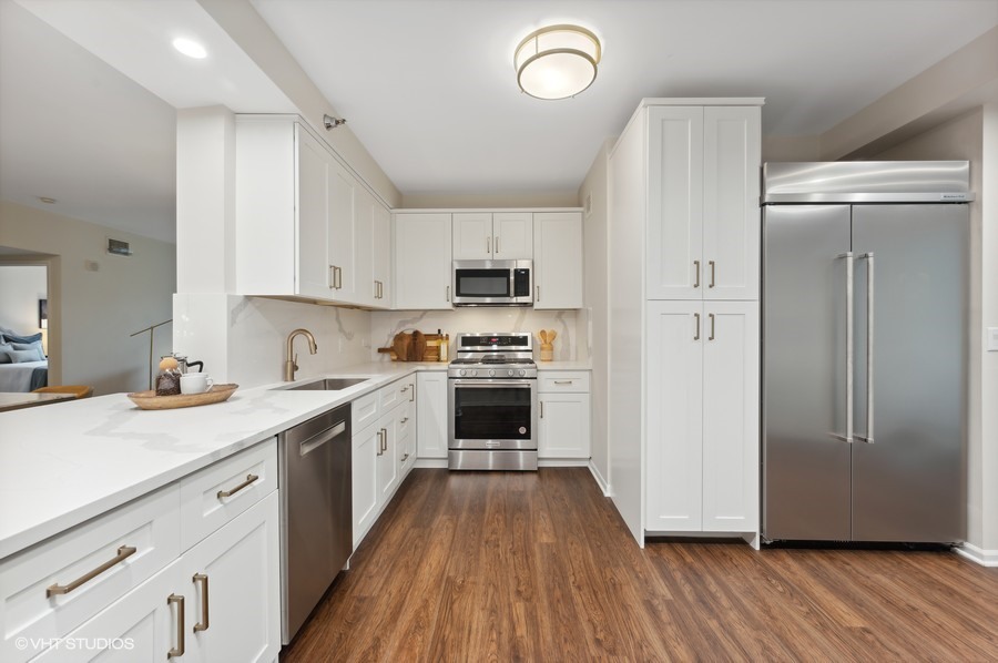 55 West Delaware Place, Unit 415 Chicago, IL 60610 - Photo 10 of 41 a kitchen with a refrigerator a stove top oven a sink and dishwasher with wooden floor