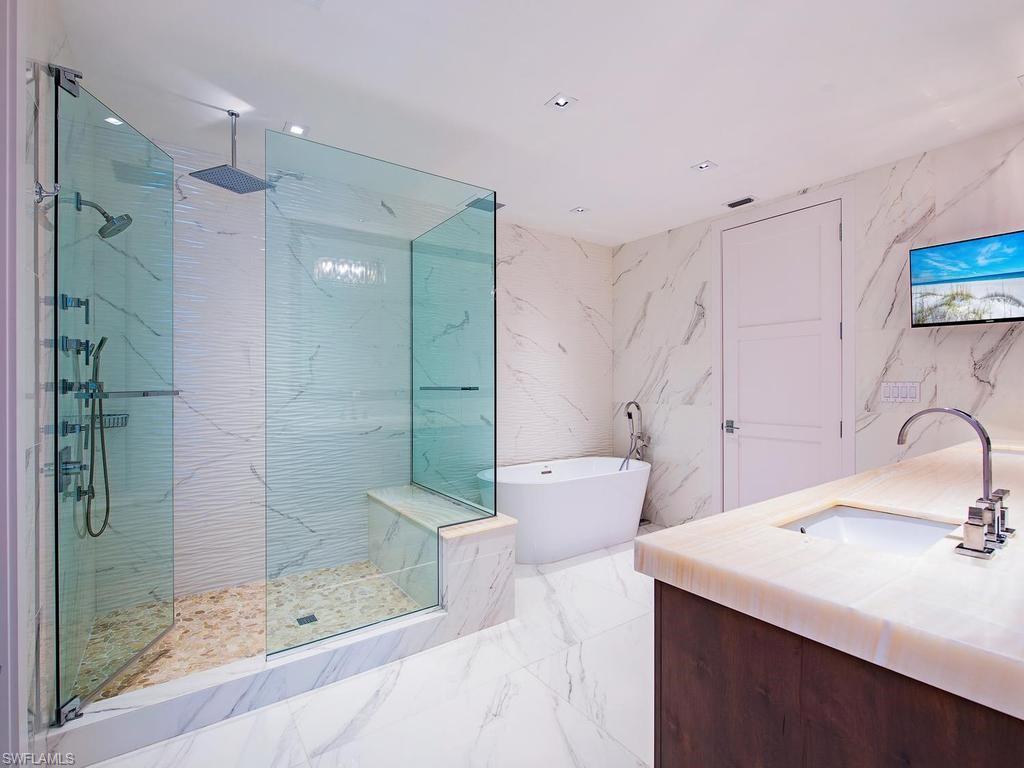 490 5th Street South, Unit 101 Naples, FL 34102 - Photo 13 of 34 a bathroom with a bathtub shower sink mirror and toilet