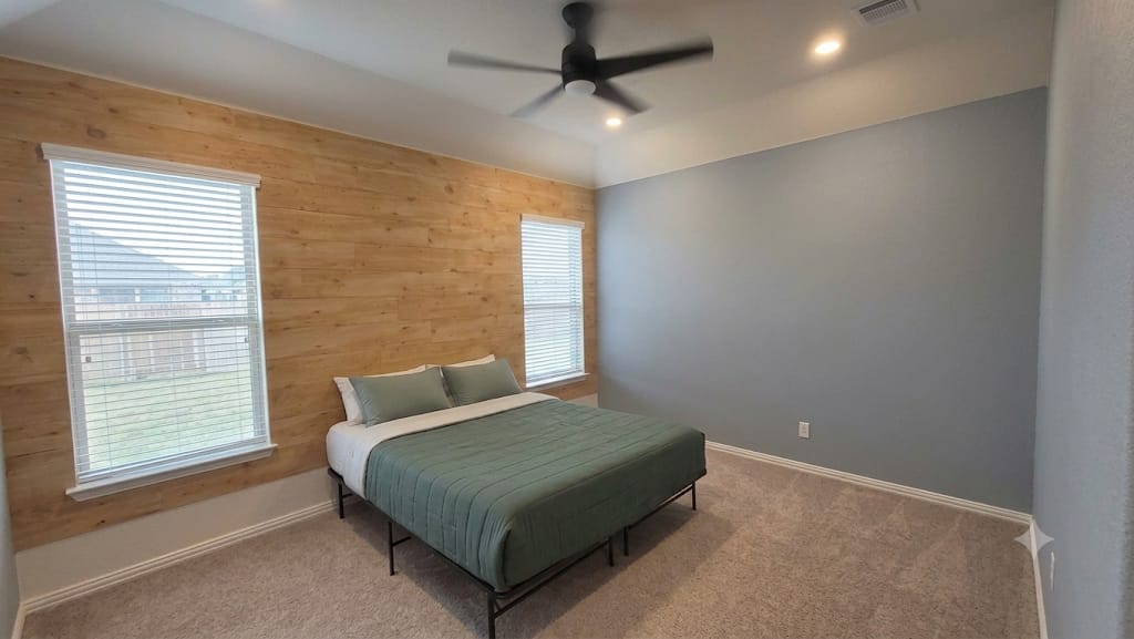 A spacious bedroom features natural wood wall paneling alongside plush neutral carpeting.