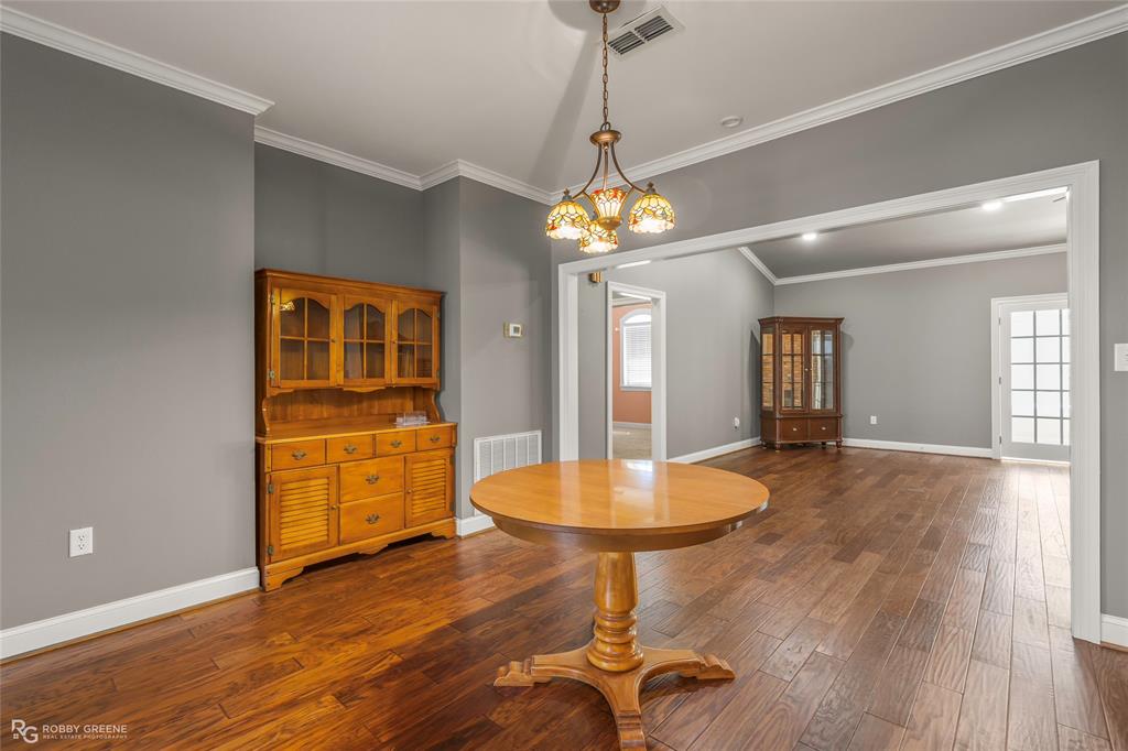703 Airport Loop Homer, LA 71040 - Photo 11 of 32 a dining room with wooden floor a chandelier a glass table and chairs