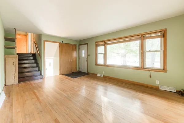 a view of an empty room with wooden floor and a window