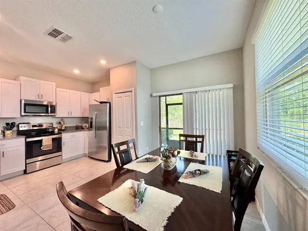 a large kitchen with a table chairs stove a refrigerator and cabinets