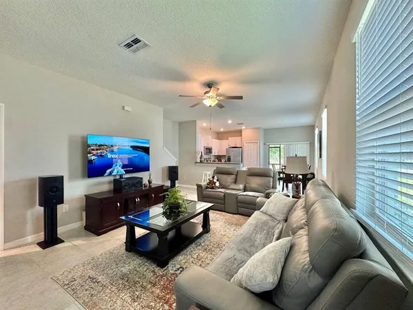 a living room with furniture a flat screen tv and a window
