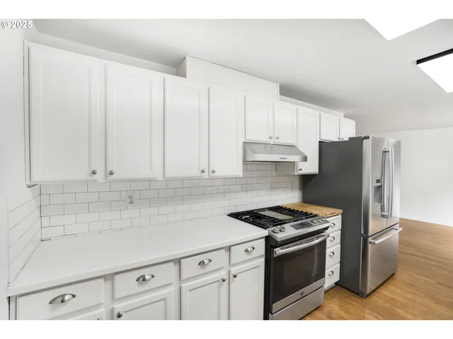 a kitchen with granite countertop a refrigerator stove and white cabinets