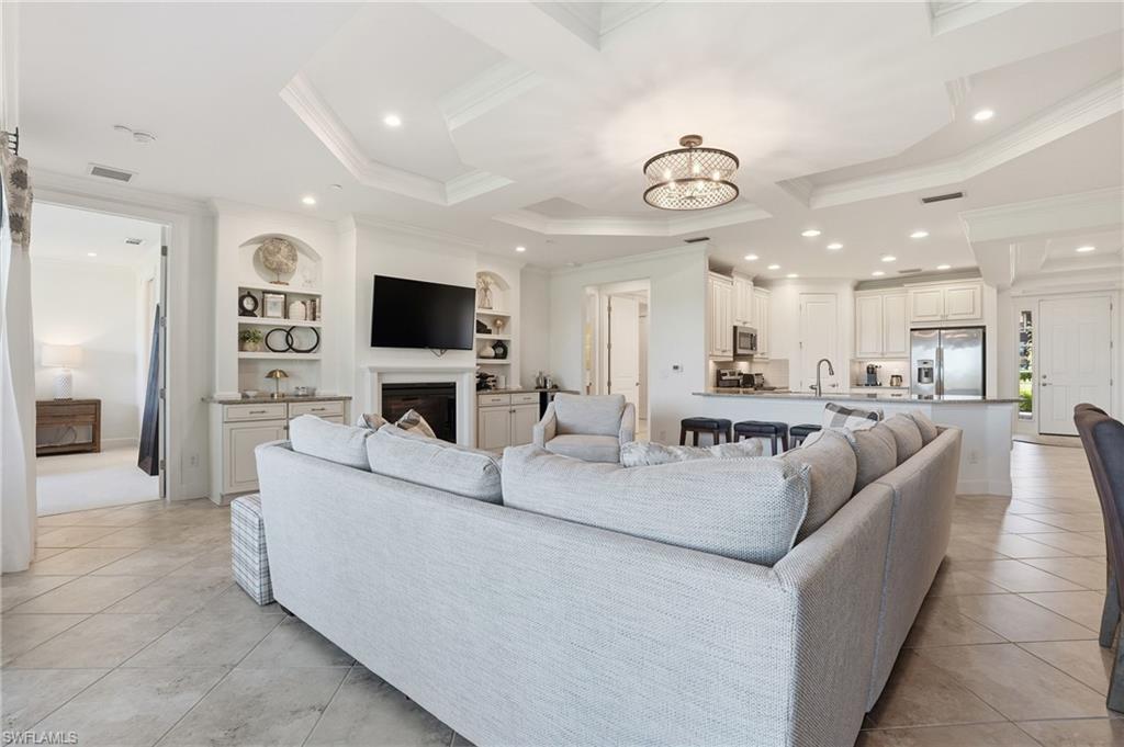 8773 Bellano Court, Unit 103 Naples, FL 34119 - Photo 13 of 47 Living area featuring built in features, a chandelier, light tile patterned floors, a fireplace, and ornamental molding