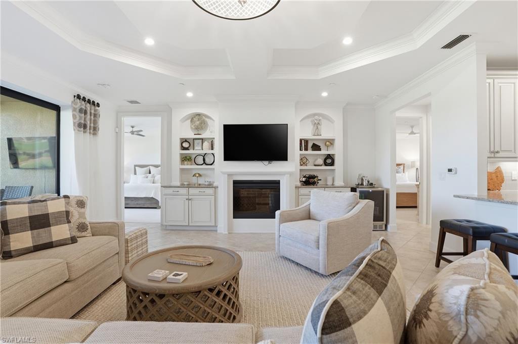 8773 Bellano Court, Unit 103 Naples, FL 34119 - Photo 14 of 47 Living area featuring built in features, light tile patterned floors, a glass covered fireplace, recessed lighting, and crown molding