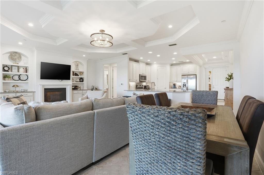 8773 Bellano Court, Unit 103 Naples, FL 34119 - Photo 16 of 47 Living room with built in shelves, a chandelier, a fireplace, recessed lighting, and ornamental molding