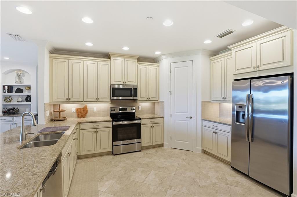 8773 Bellano Court, Unit 103 Naples, FL 34119 - Photo 20 of 47 Kitchen featuring cream cabinetry, stainless steel appliances, light stone countertops, ornamental molding, and recessed lighting