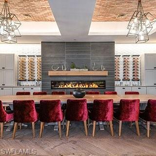 8773 Bellano Court, Unit 103 Naples, FL 34119 - Photo 42 of 47 Dining space with a raised ceiling, a chandelier, a fireplace, brick ceiling, and light wood-type flooring