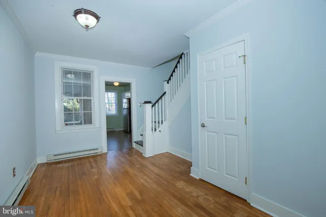 an empty room with wooden floor chandelier fan and windows