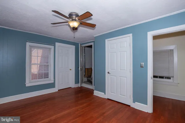 an empty room with wooden floor closet and windows
