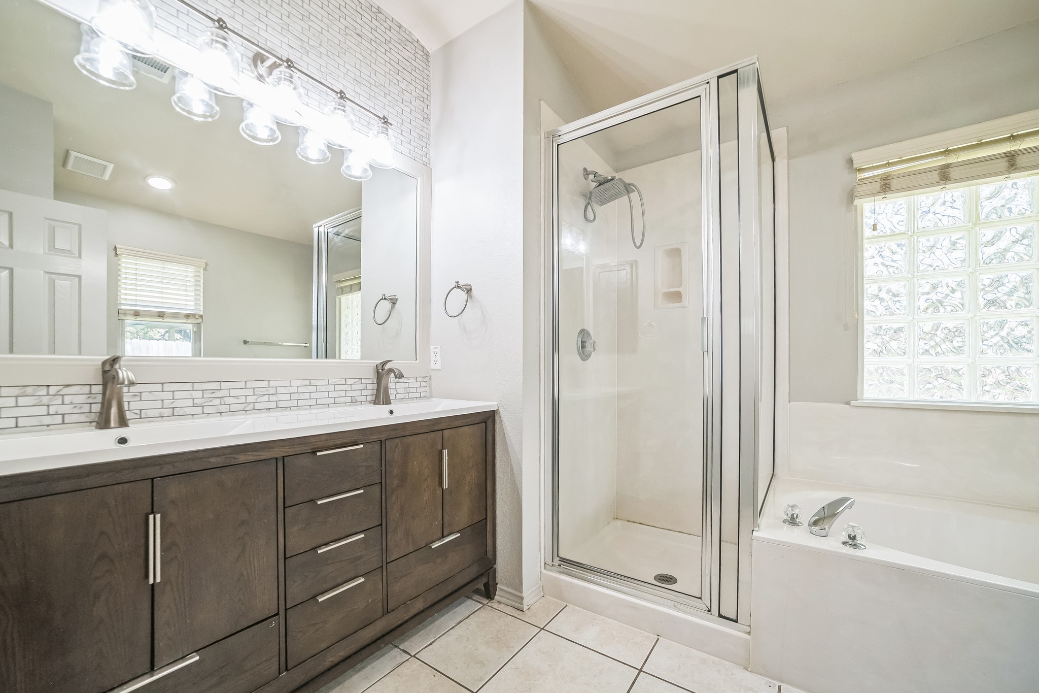 3630 Spring Canyon Trail Round Rock, TX 78681 - Photo 9 of 23 Full bath with tasteful backsplash, double vanity, a shower stall, light tile patterned flooring, and a bath
