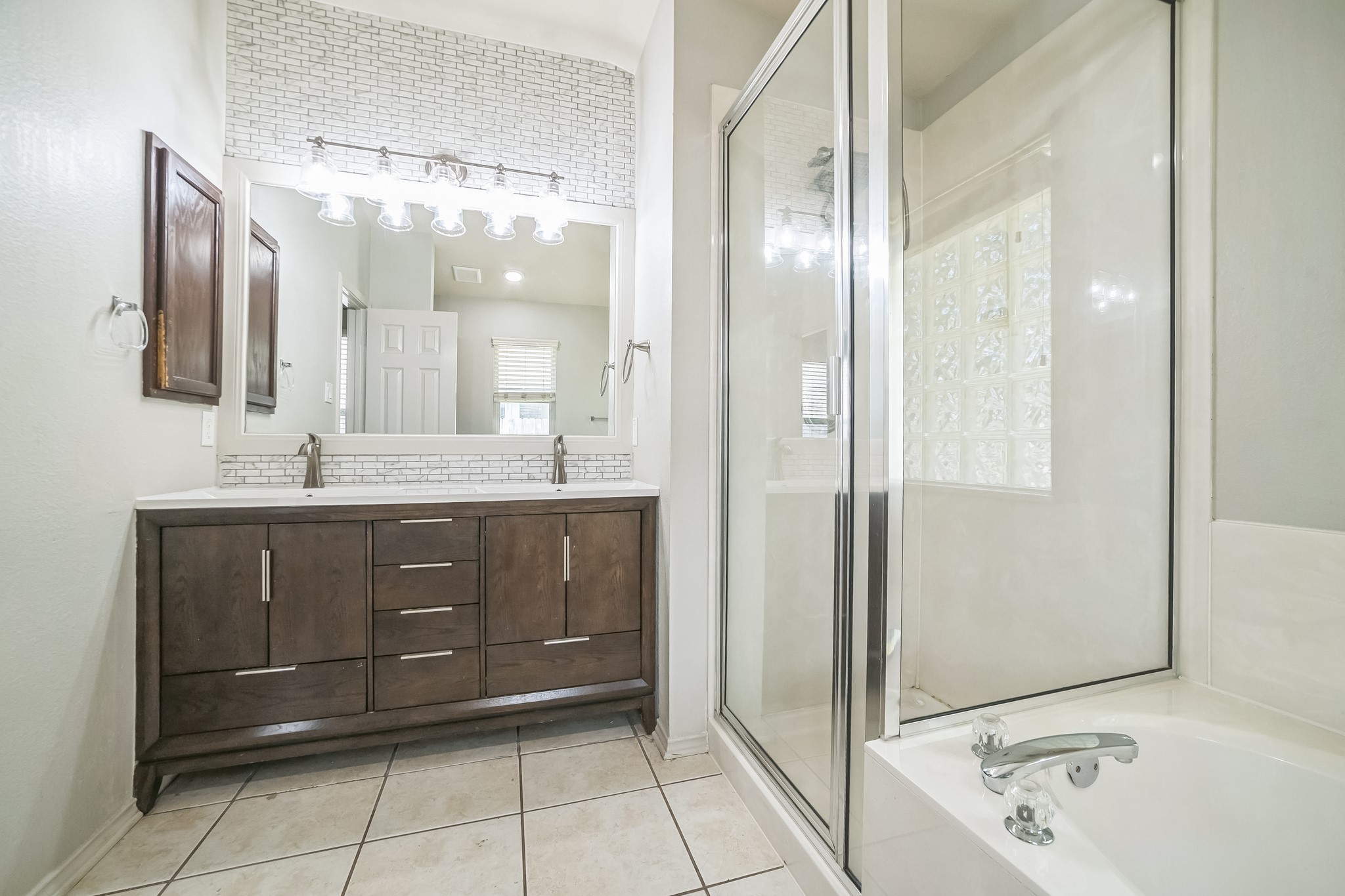3630 Spring Canyon Trail Round Rock, TX 78681 - Photo 18 of 23 Bathroom with double vanity, light tile patterned flooring, decorative backsplash, a shower stall, and a garden tub