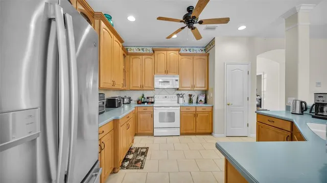 a kitchen with stainless steel appliances granite countertop a refrigerator a sink dishwasher and white cabinets next to a window
