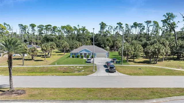a view of a house with a yard and trees in the background