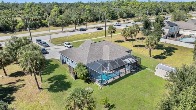 a view of a swimming pool with a yard and large trees