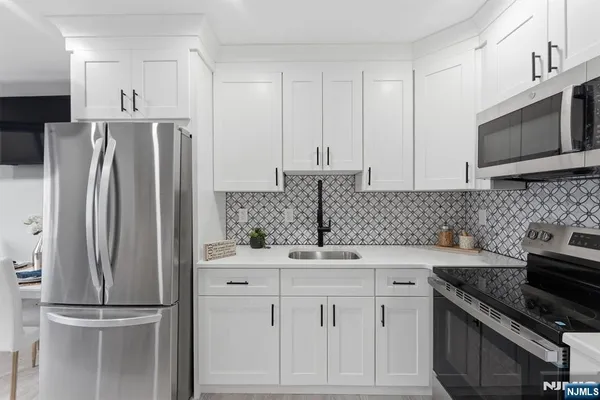 a kitchen with white cabinets sink and stainless steel appliances