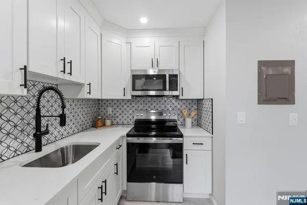 a kitchen with granite countertop a stove sink and microwave