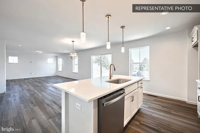 a large kitchen with stainless steel appliances granite countertop a stove a refrigerator a sink and a wooden floor