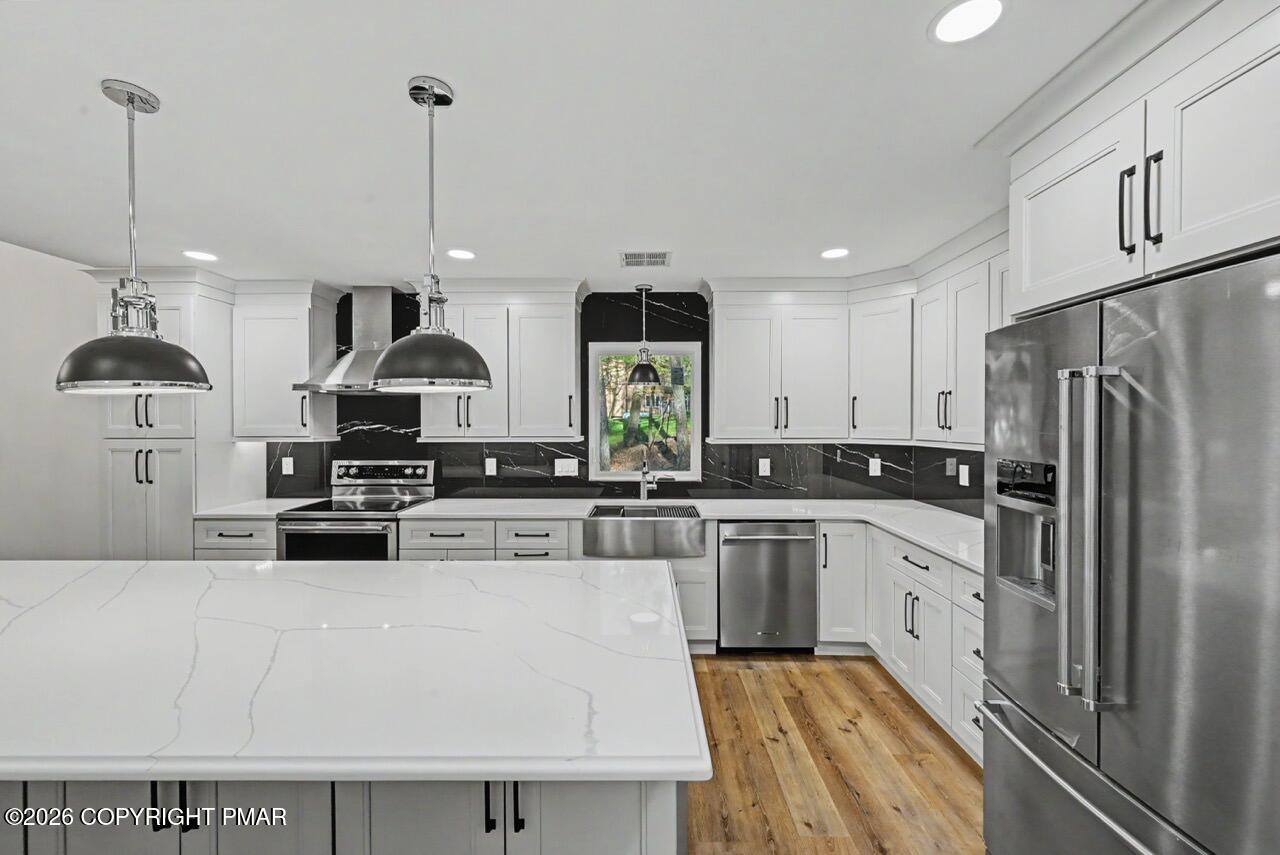1131 Mink Court Bushkill, PA 18324 - Photo 29 of 81 a kitchen with stainless steel appliances granite countertop a sink a stove a refrigerator and island with wooden floor