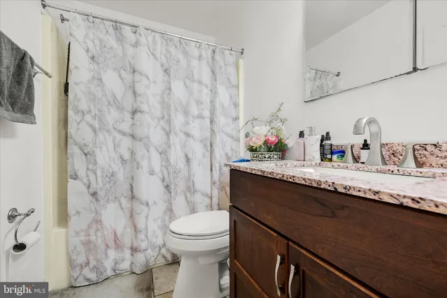 a bathroom with a granite countertop sink and a toilet