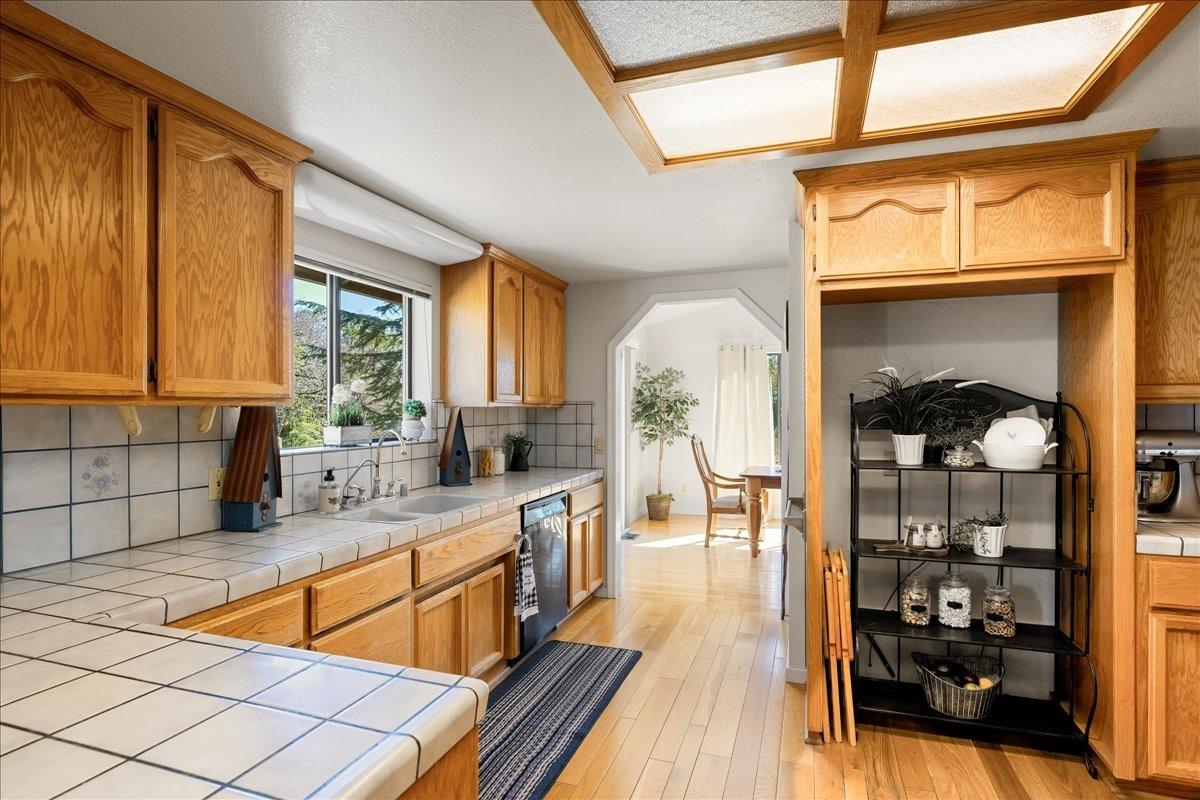 13936 Oak Ridge Road Penn Valley, CA 95946 - Photo 21 of 83 a kitchen with stainless steel appliances wooden cabinets a stove a sink and a dining table with wooden floor
